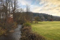 A sunlit valley, early in the morning, with a pretty little creek running through.